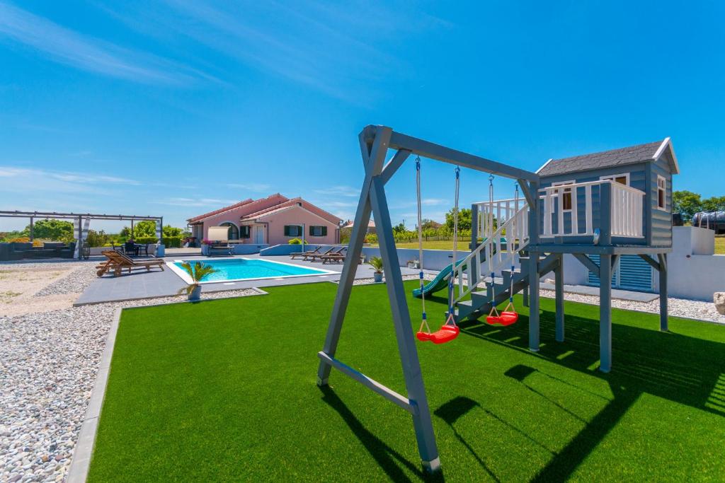 a playground with a swing and a pool at Villa Perini Dvori in Donji Zemunik
