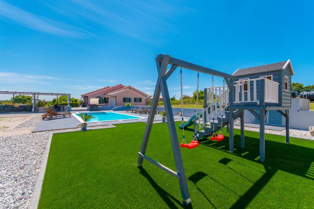 un parque infantil con un columpio y una piscina en Villa Perini Dvori, en Donji Zemunik