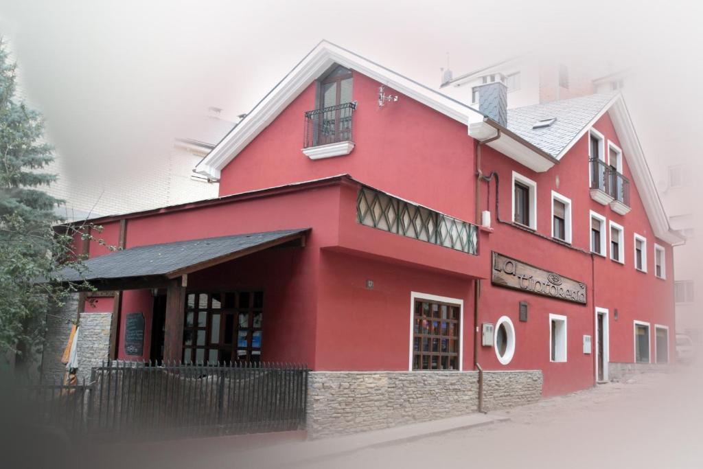 un edificio rojo al lado de una calle en Hostal Rural La Tintoreria en Villablino
