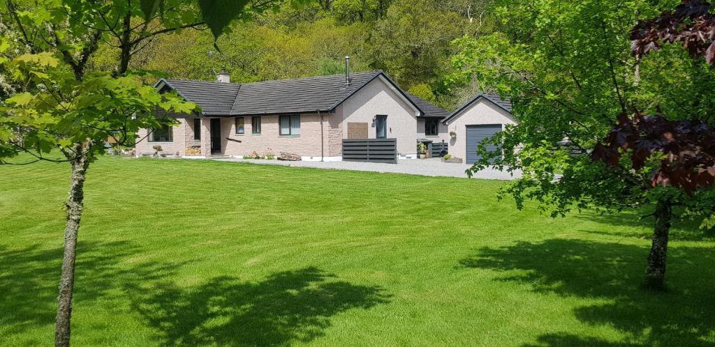 een huis in een tuin met een groen gazon bij Ridgewood Apartment in Drumnadrochit