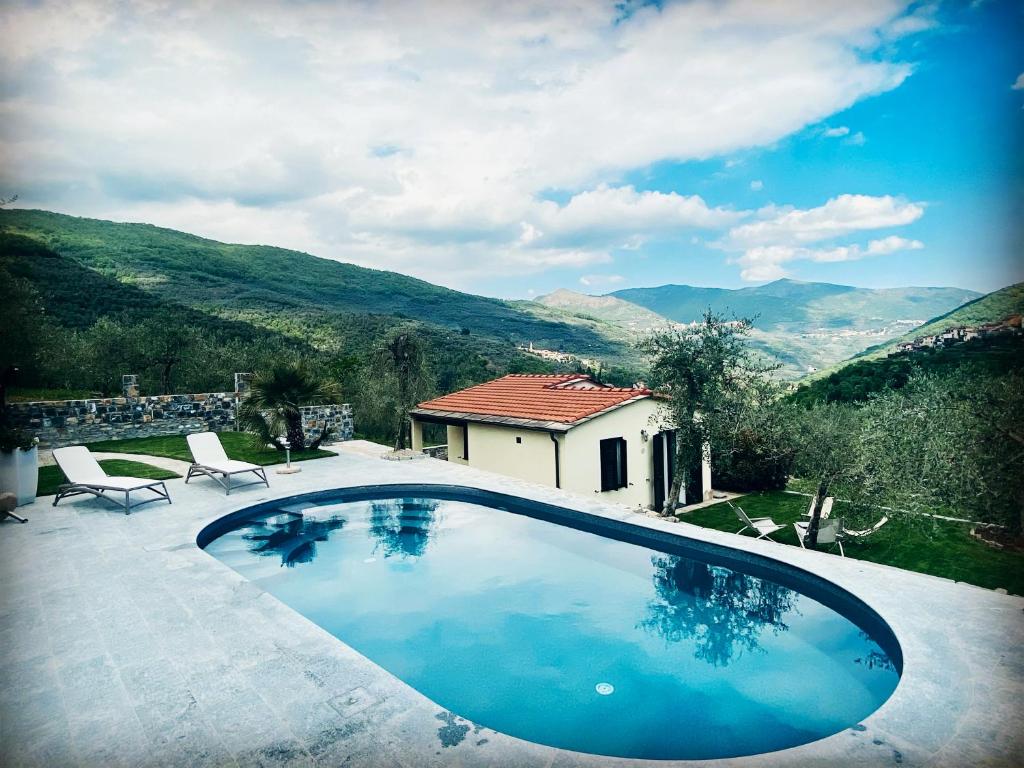 a swimming pool with a view of a house and mountains at Casa vacanze gli ulivi in Borgomaro