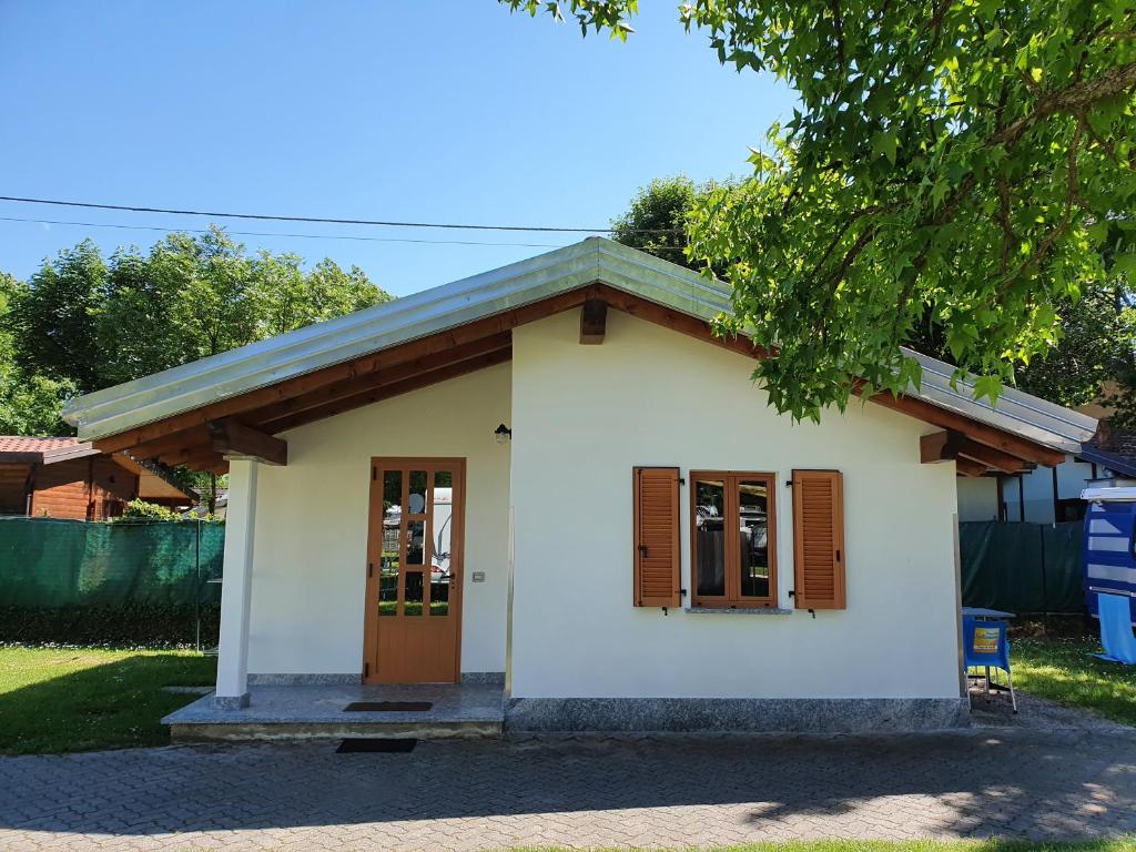 una pequeña casa blanca con puerta y ventana en Bungalows in Camping Solarium en Domaso