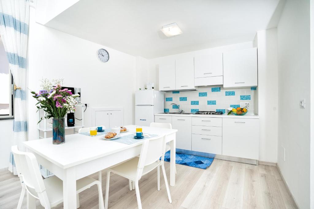 a white kitchen with a white table and chairs at Casa Acqua Marina in Amalfi