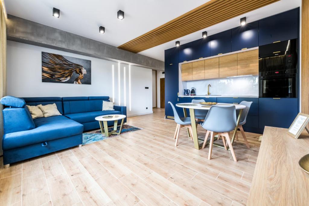 uma sala de estar com um sofá azul e uma mesa em Golden Apartament - Żeglarska em Giżycko