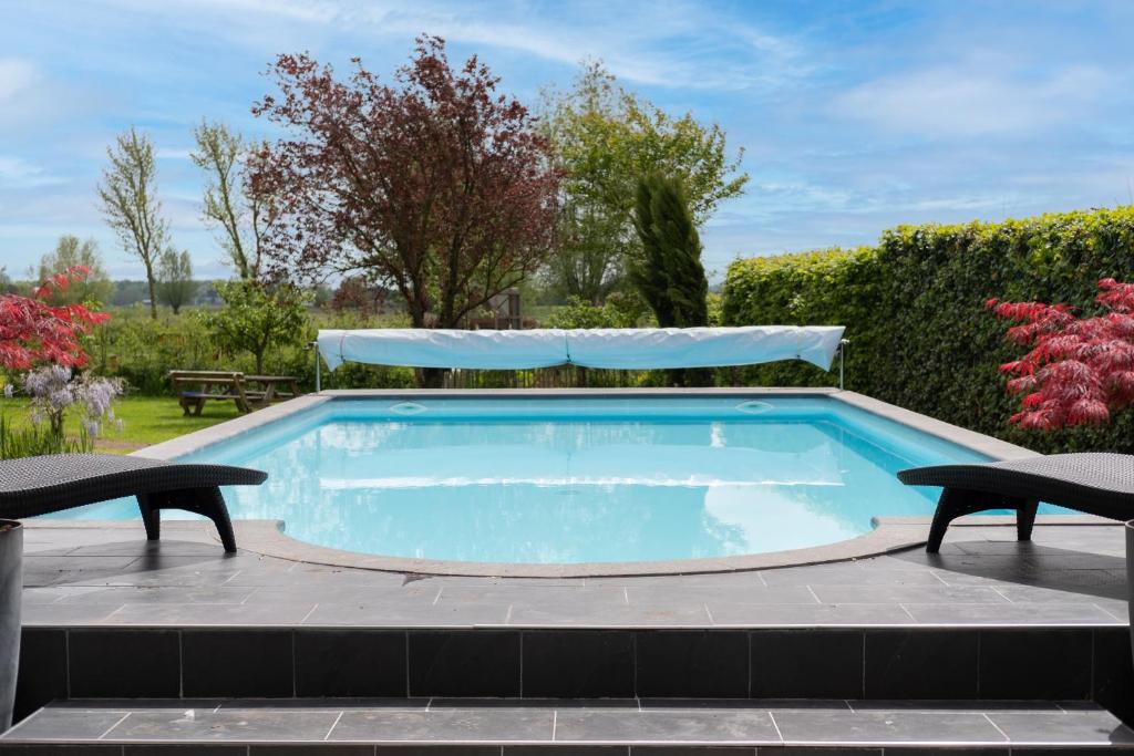 una piscina con 2 sillas y una mesa en Bed & Breakfast De Heughte, en Oosterwolde