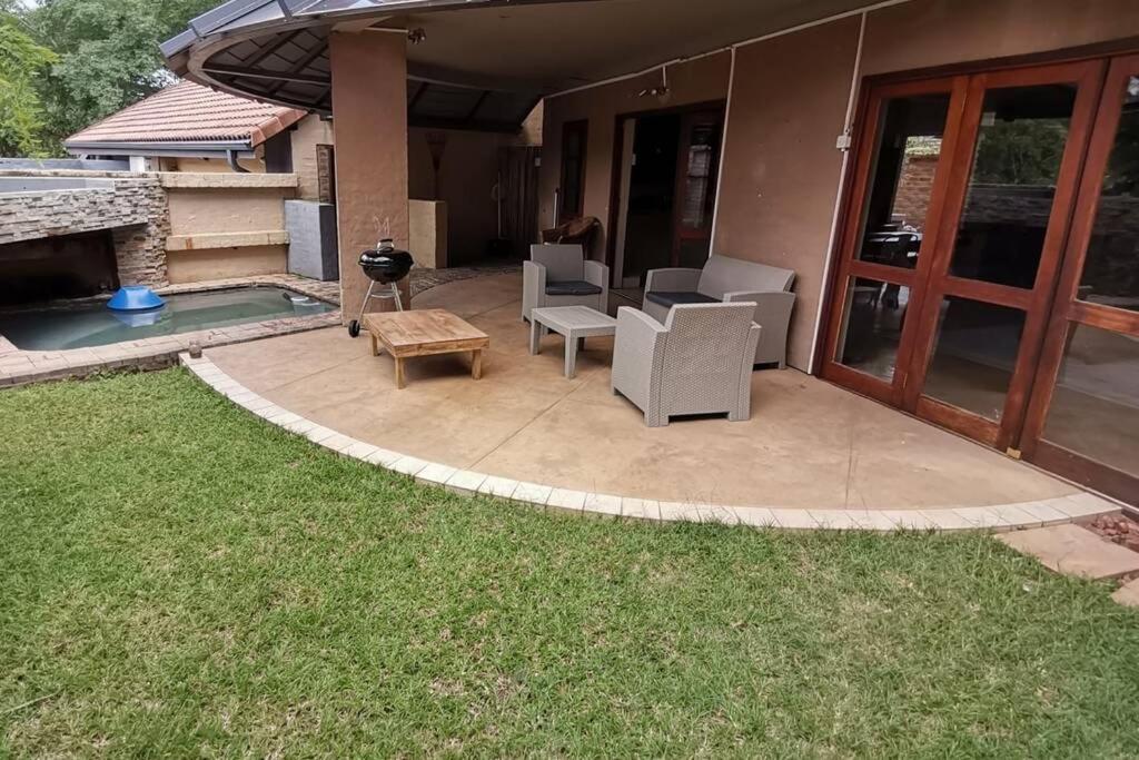 a patio with chairs and a table and a pool at Luxury Villa Nelspruit in Nelspruit