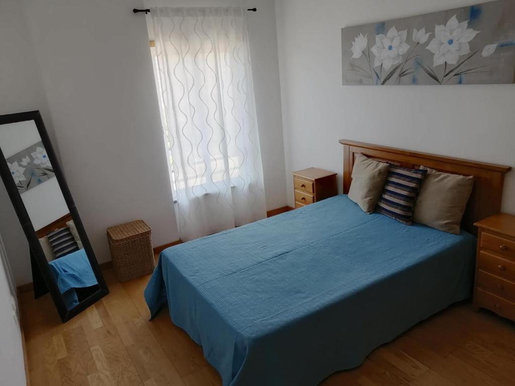 アルマカオ・デ・ペラにあるApartamento Brisa Marのベッドルーム(青いベッド1台、鏡付)
