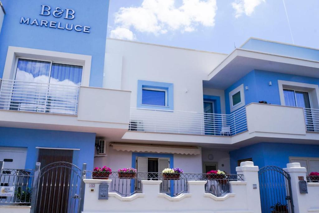 - un bâtiment bleu et blanc avec des fleurs sur les balcons dans l'établissement Mareluce B&B, à Porto Cesareo