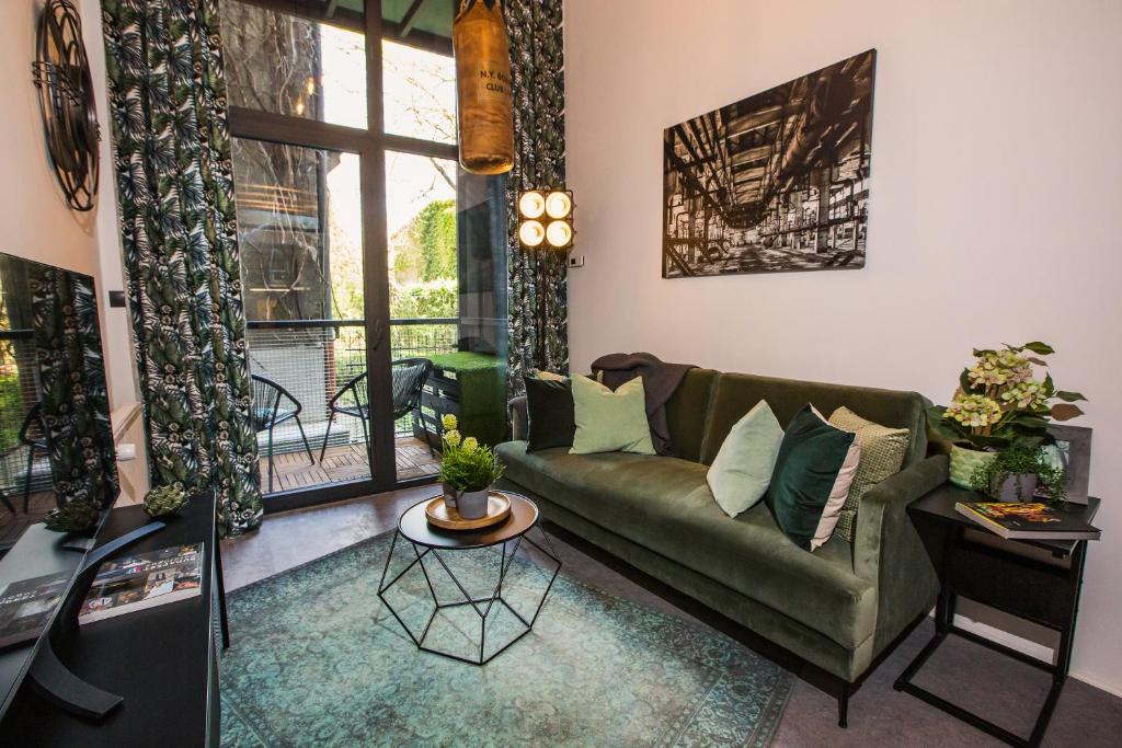 a living room with a green couch and a table at UrbanJungle - Your trendy loft in central Budapest in Budapest