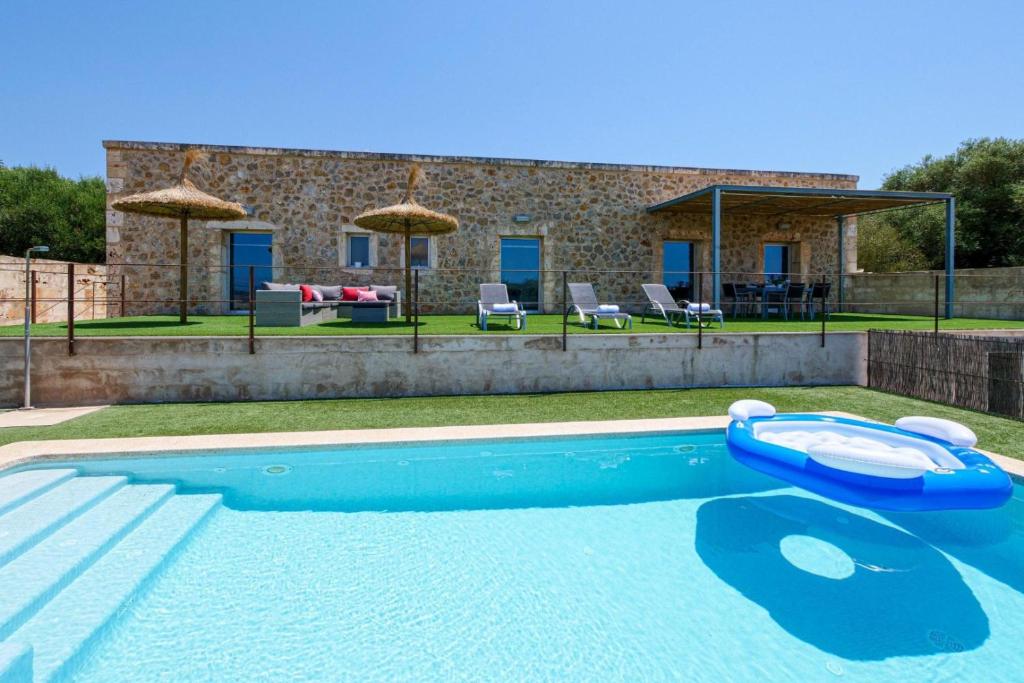 una piscina frente a una casa de piedra en Es Gassons, en Maria de la Salut