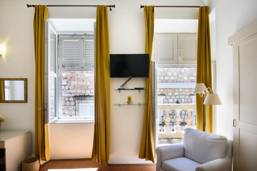sala de estar con cortinas amarillas y silla en SWEET ROOM OLD TOWN by DuHomes, en Dubrovnik