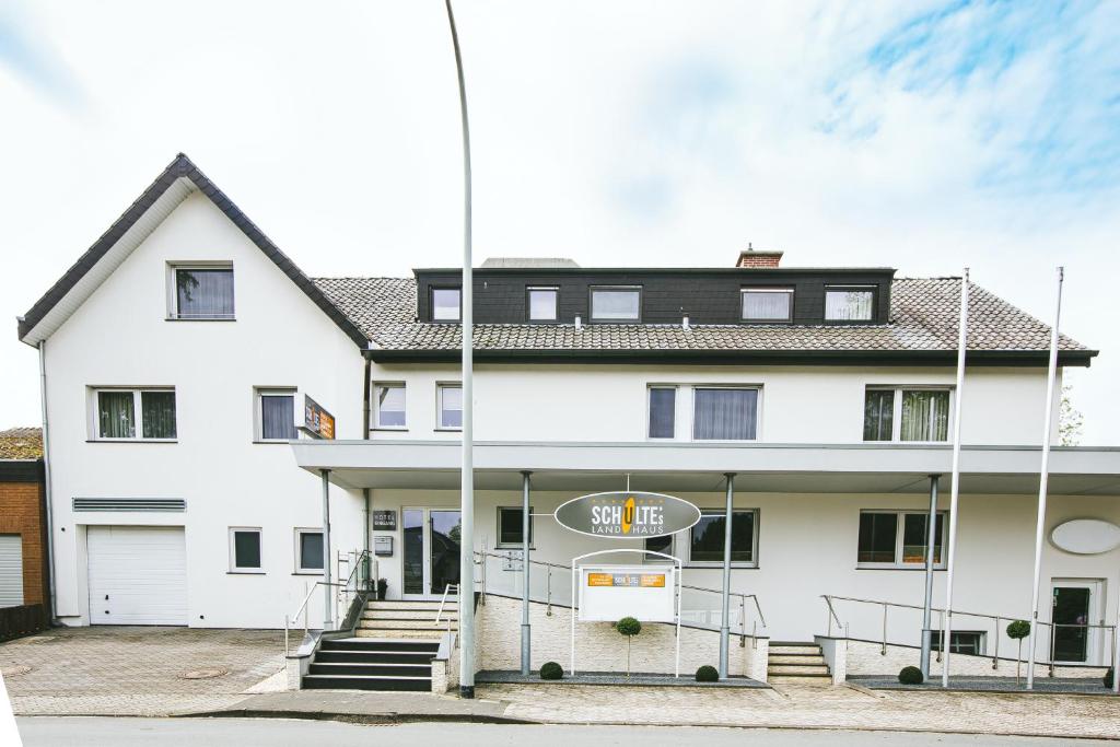 un bâtiment blanc avec un panneau devant lui dans l'établissement Schultes Landhaus, à Delbrück