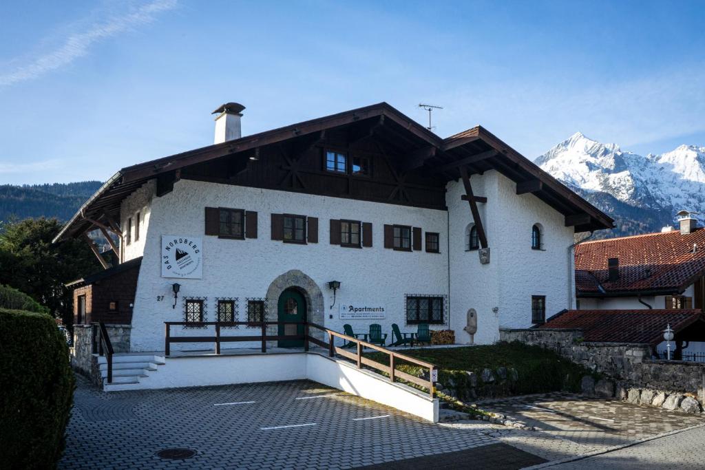 a large white building with mountains in the background at Das Nordberg Apartments in Garmisch-Partenkirchen