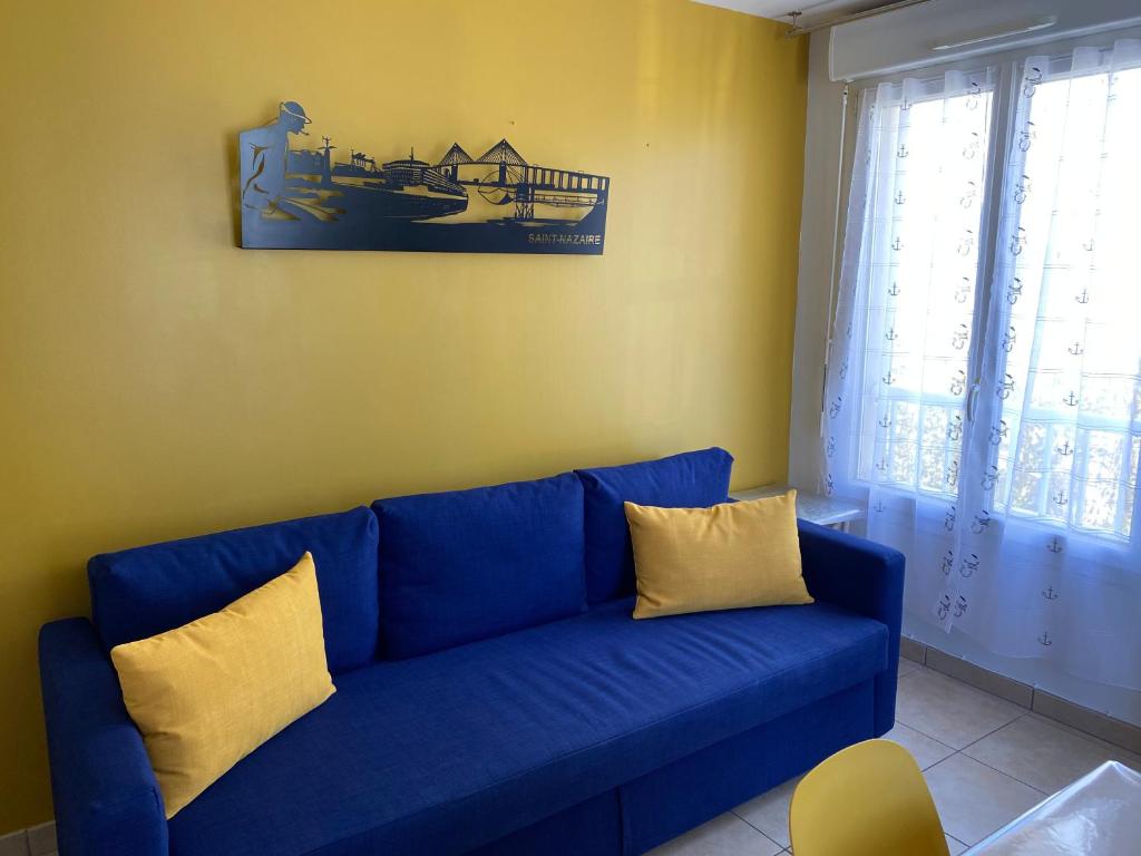 a blue couch with yellow pillows in a living room at Résidence Fort de l'Eve - T2 à 300m plage M Hulot, chemin côtier, commerces - St Marc sur Mer proche La Baule Ponichet in Saint-Nazaire