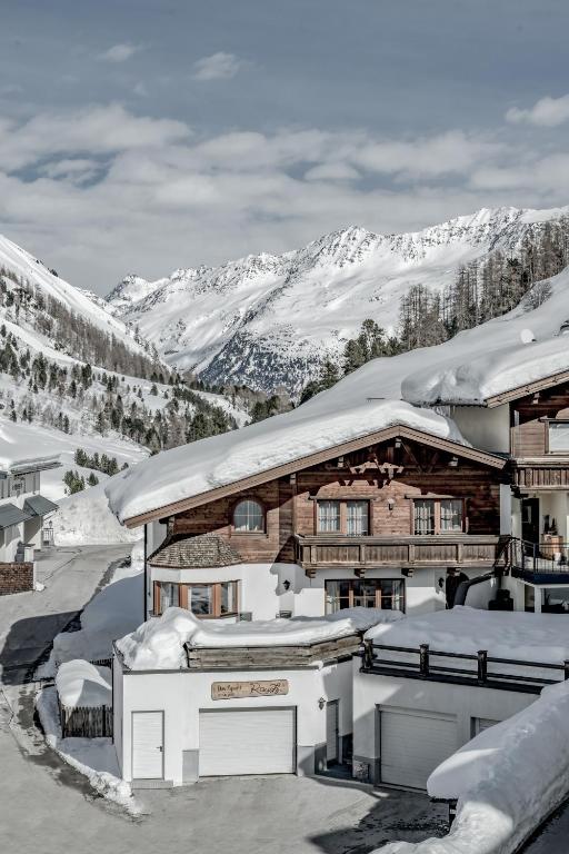 a house covered in snow with mountains in the background at Das Apart Rauch Gurgl in Obergurgl