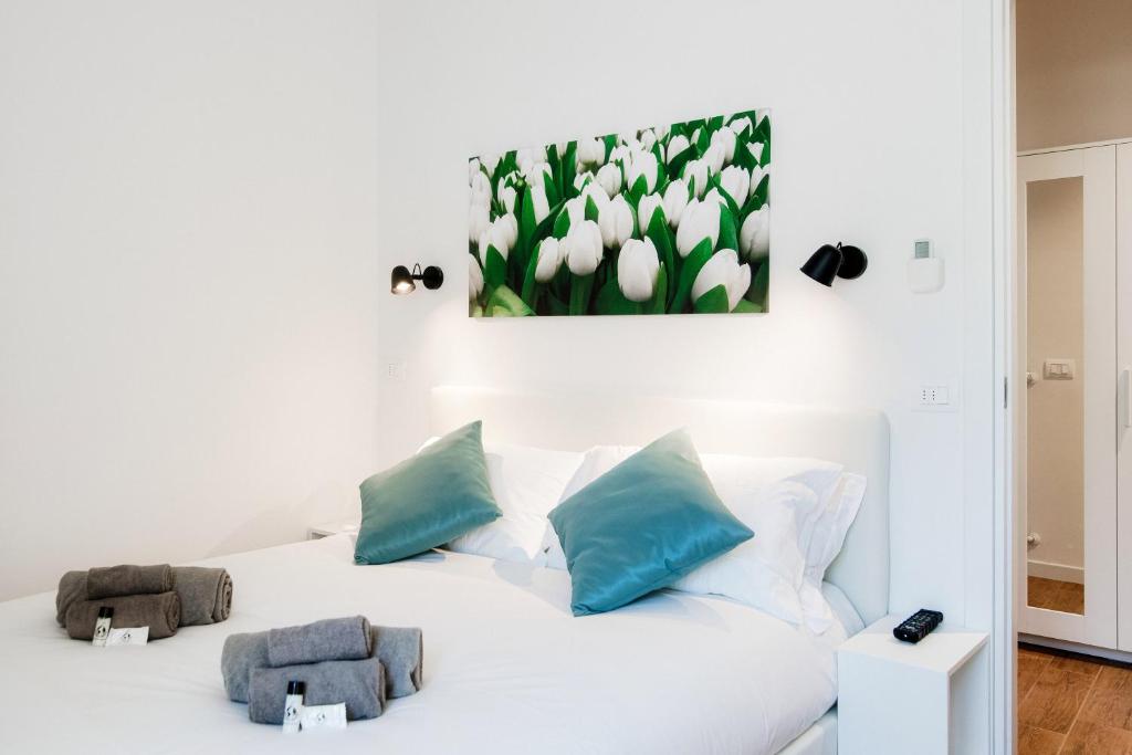 uma cama branca com almofadas azuis e uma pintura na parede em White Loft Como Central - The House Of Travelers em Como