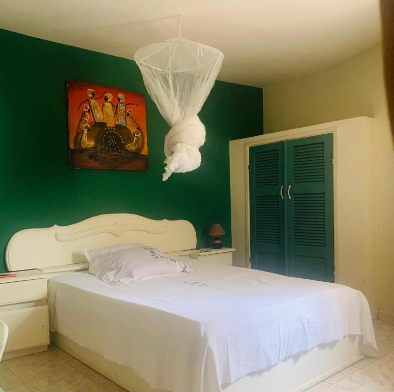 um quarto com uma cama branca e uma parede verde em Carthago em Mbour