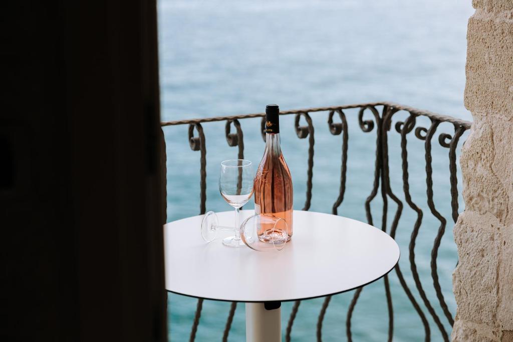 a bottle of wine and two glasses on a table at Tre Archi Suite & Relais in Polignano a Mare