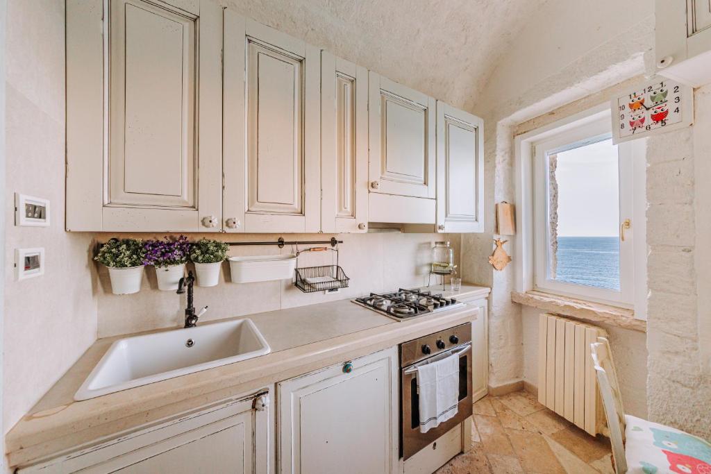 a kitchen with white cabinets and a sink and a window at Tre Archi Suite & Relais in Polignano a Mare