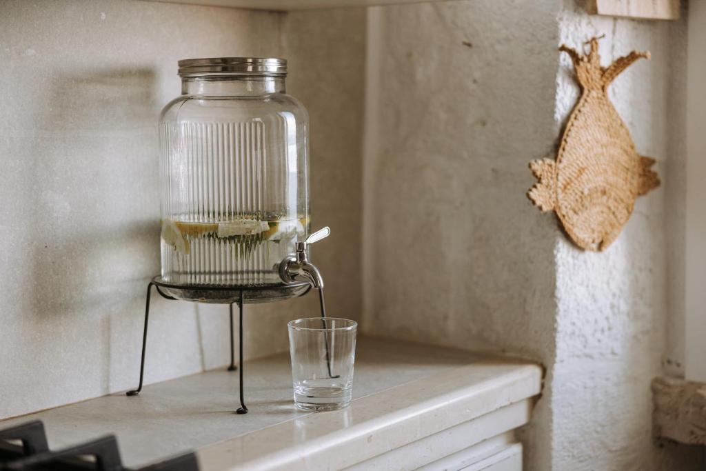 a glass jar sitting on top of a counter next to a glassapsed at Tre Archi Suite & Relais in Polignano a Mare