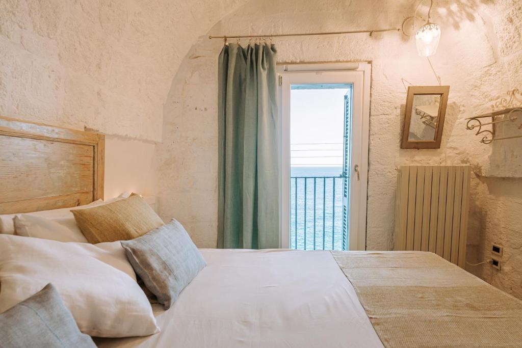 a bedroom with a large bed with a window at Tre Archi Suite & Relais in Polignano a Mare