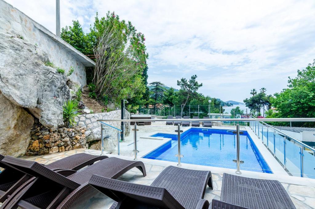 a swimming pool with chairs and a rock wall at Villa Babilon in Zaton