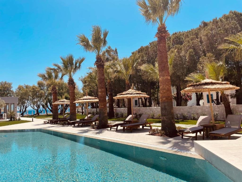 - une piscine avec des chaises, des parasols et des palmiers dans l'établissement Regia Mare Beach Hotel Bodrum, à Ortakent