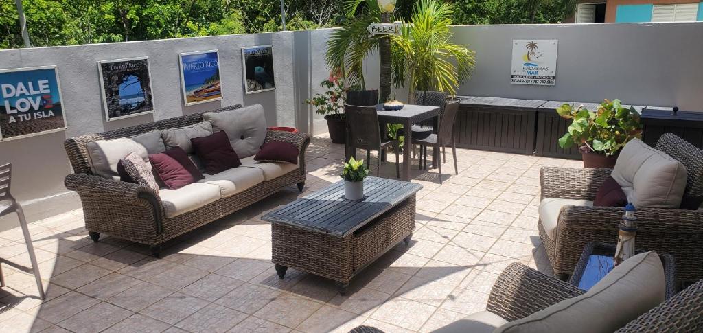 un patio con sillas de mimbre, mesa y mesa en Palmeras Del Mar en Isabela