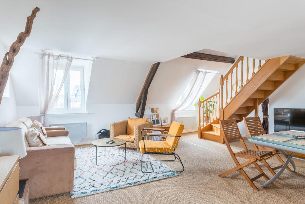 ein Wohnzimmer mit weißen Wänden und einer Treppe in der Unterkunft Le Teck in Deauville