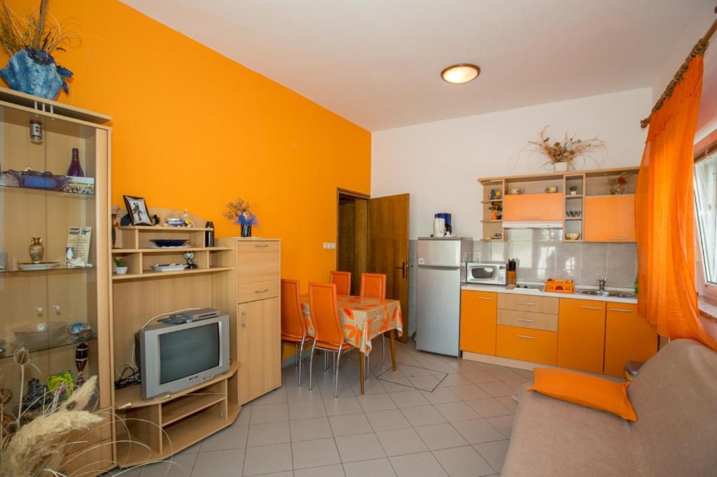 a kitchen with orange walls and a tv in it at House Lopar (73) in Lopar