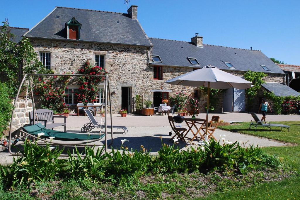 a patio with chairs and an umbrella in front of a building at Gîte Ti ar Rozenn in Mont-Dol