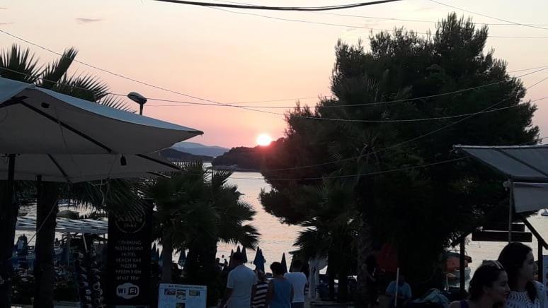 Hotel Adriatik Ksamil في كساميل: مجموعة من الناس يمشون في شارع مع غروب الشمس