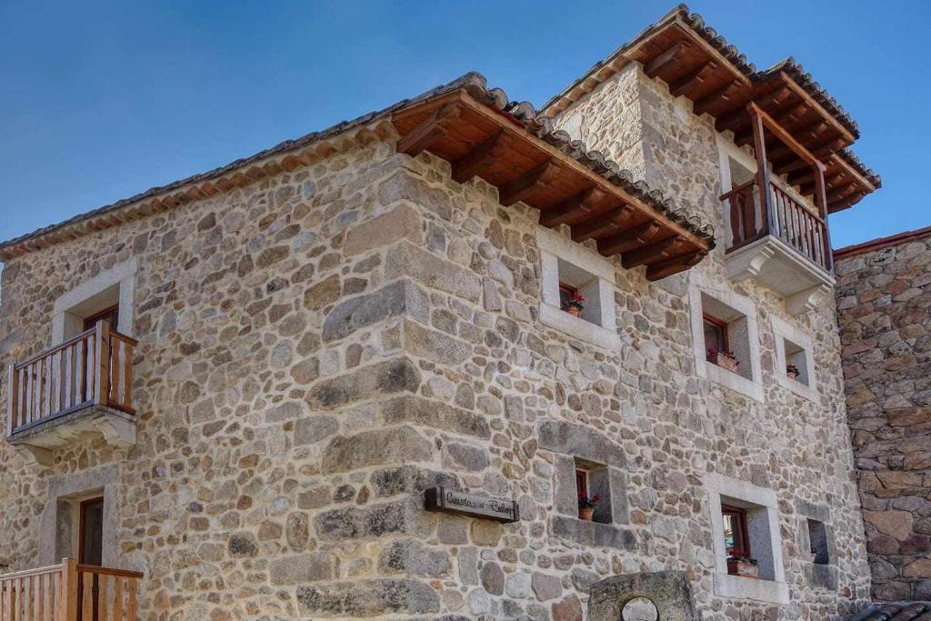 a large stone building with windows and a roof at Casa Cuesta del Reloj in Piedralaves