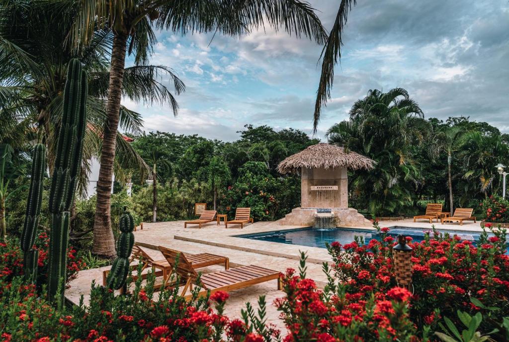 a swimming pool with a gazebo and chairs and flowers at Drift Away Lodge in Playa Avellana