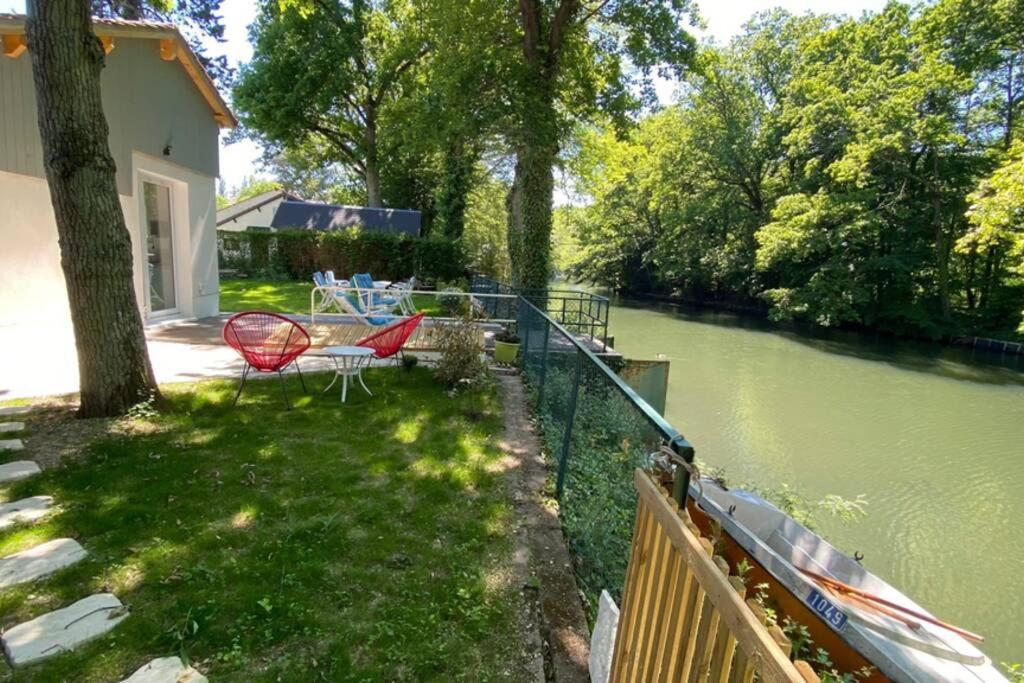 a yard with a table and chairs next to a river at Loire Nature, proche de la ville in Orléans