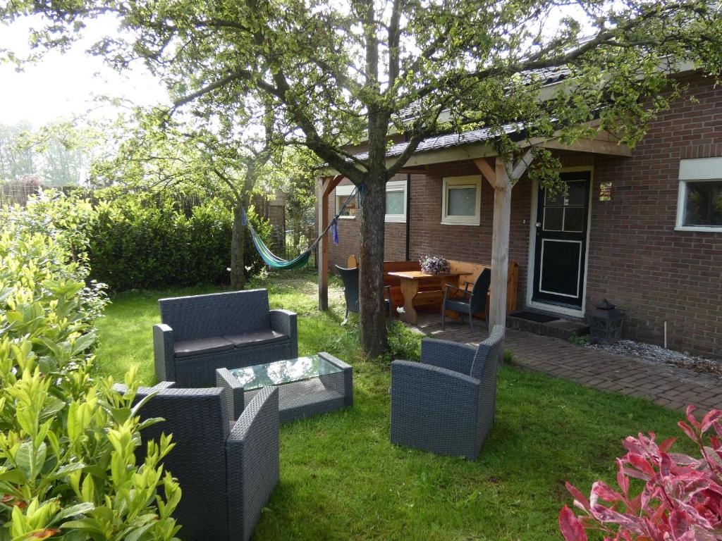 einen Hof mit zwei Stühlen, einem Tisch und einem Baum in der Unterkunft Familiehuis Achter de Duijnhoeve Bakkum in Zuidbakkum