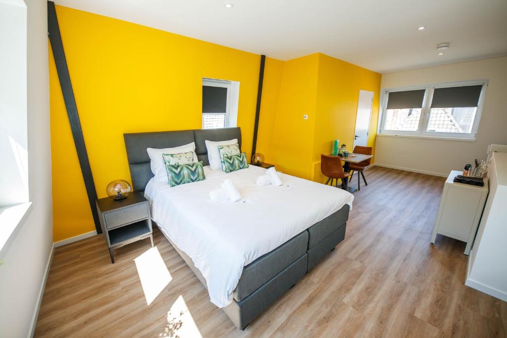 1 dormitorio con 1 cama grande y paredes amarillas en Deluxe 35m2 City Center Suite - with Views en Den Bosch