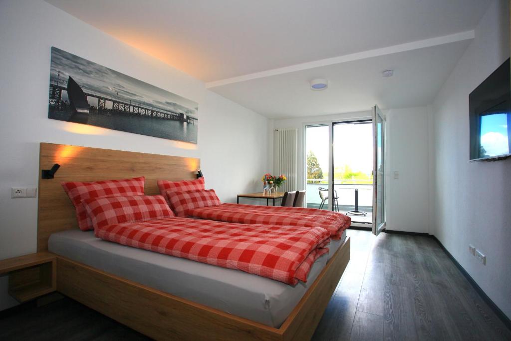 1 dormitorio con 1 cama con manta de cuadros roja en Überlinger See-Apartments Apartment 2 Über-See, en Überlingen
