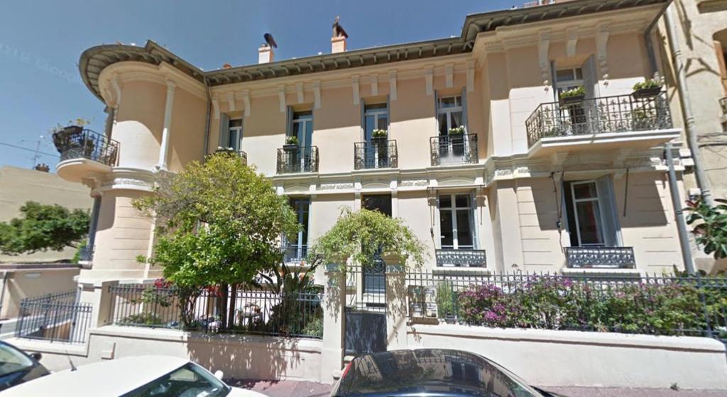 un grand bâtiment avec des voitures garées devant dans l'établissement Au petit Marius, à Cannes