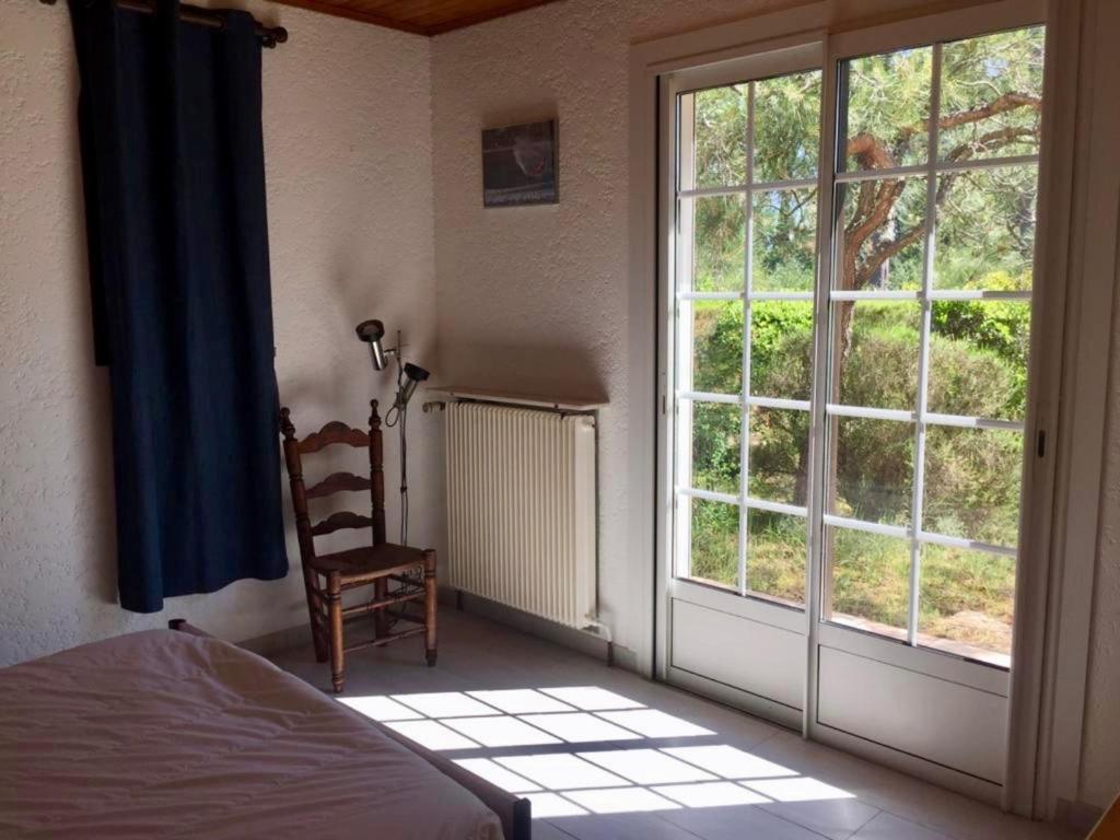 a bedroom with a window and a bed and a chair at Cottage with a big idyllic garden at the lake in Lacanau