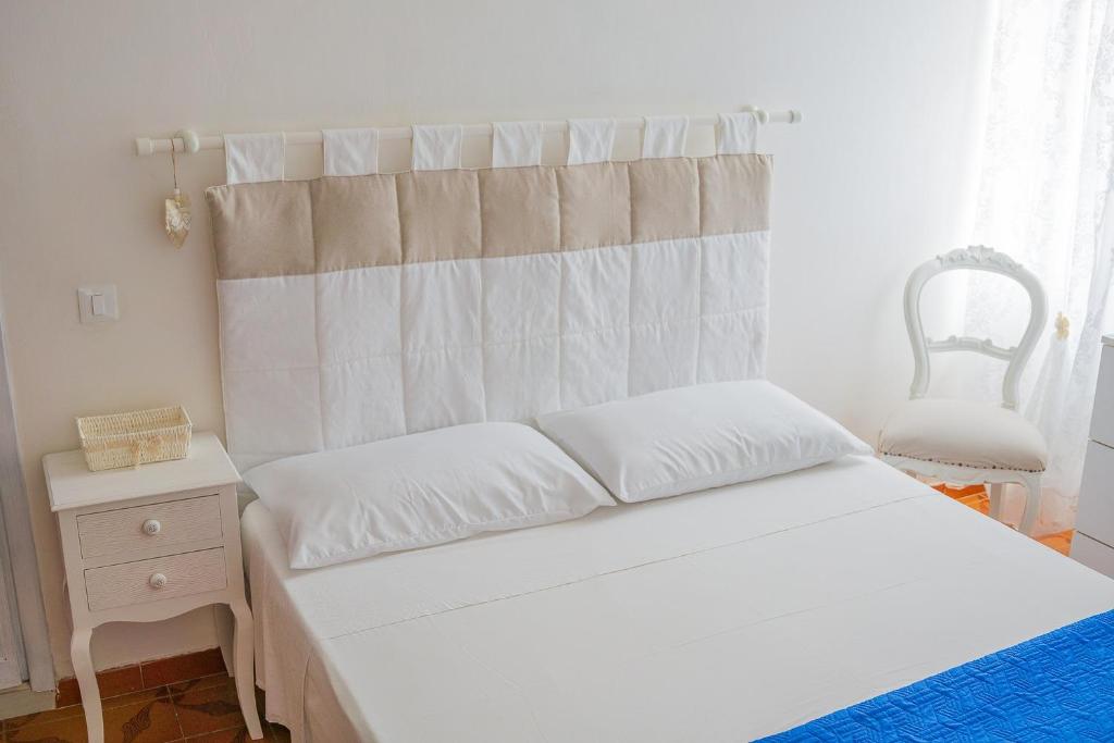 a bedroom with a white bed and a chair at Casa vacanze Via Roma in San Felice Circeo