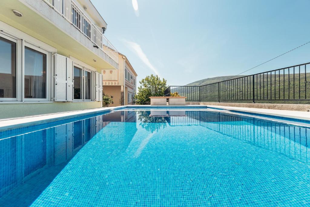 een zwembad met blauw water voor een gebouw bij VILLA ALEXANDRA in Kumbur