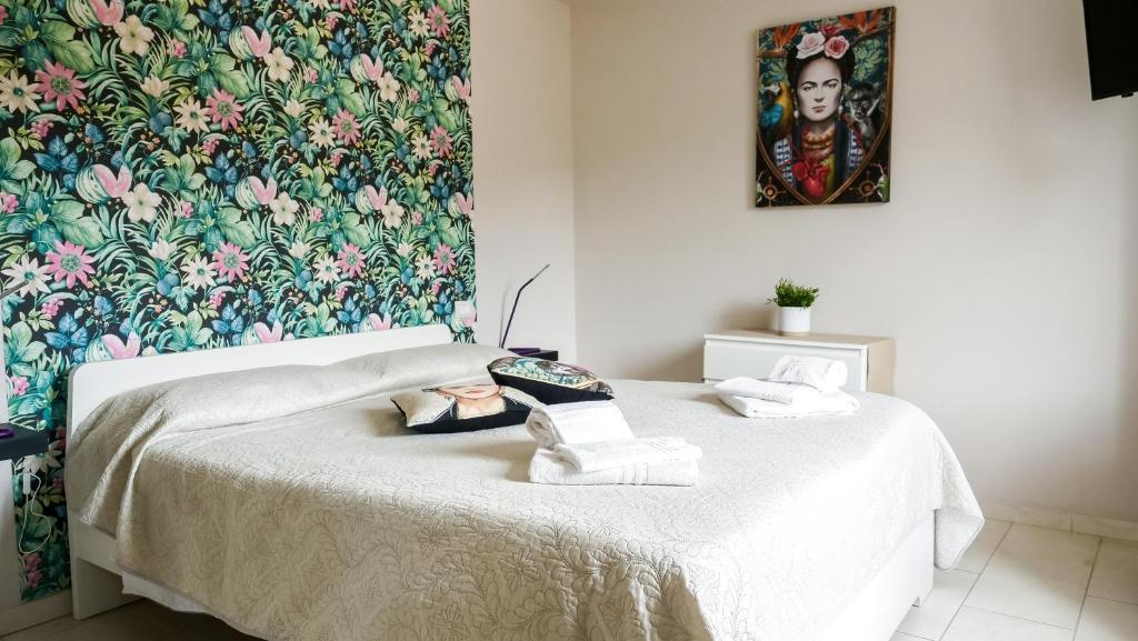 1 dormitorio con 1 cama y papel pintado con motivos florales en ApartHotel Le Sirene - FRIDA, en Tívoli