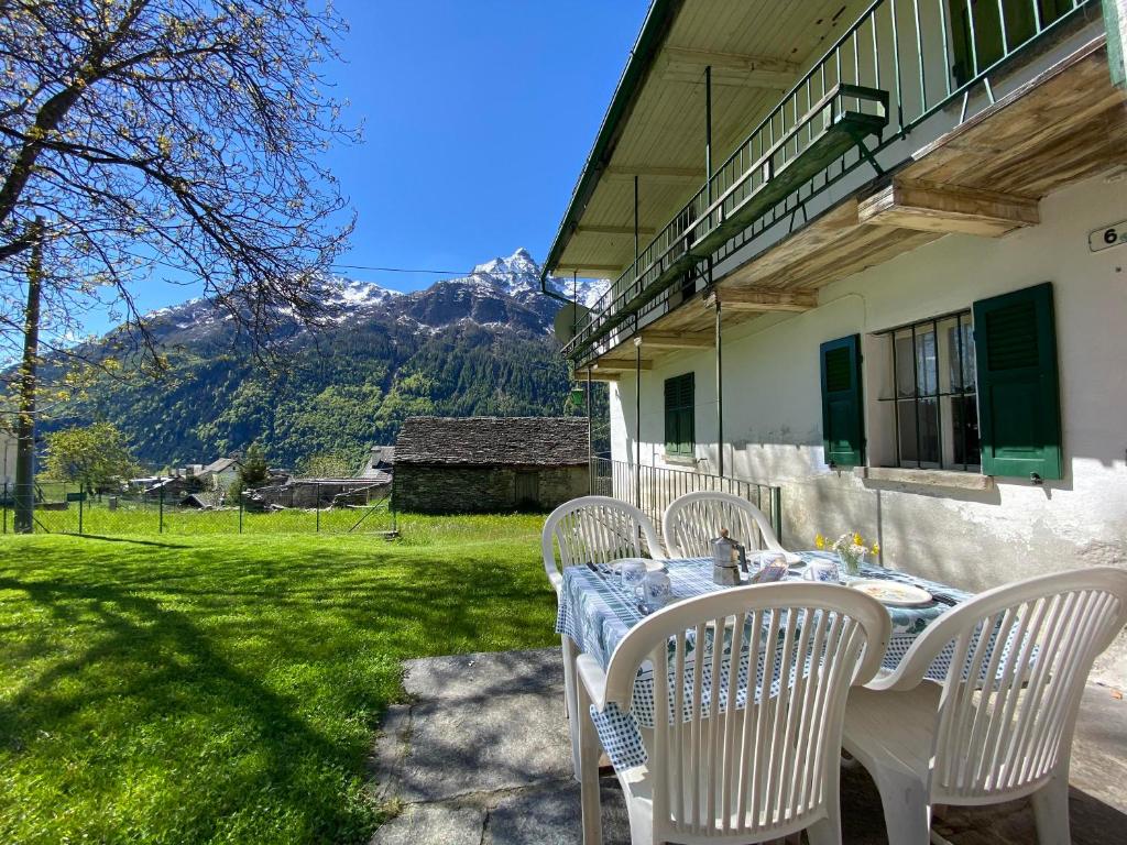 una mesa y sillas en un patio con montañas al fondo en La Casa di Sissy, en Trasquera