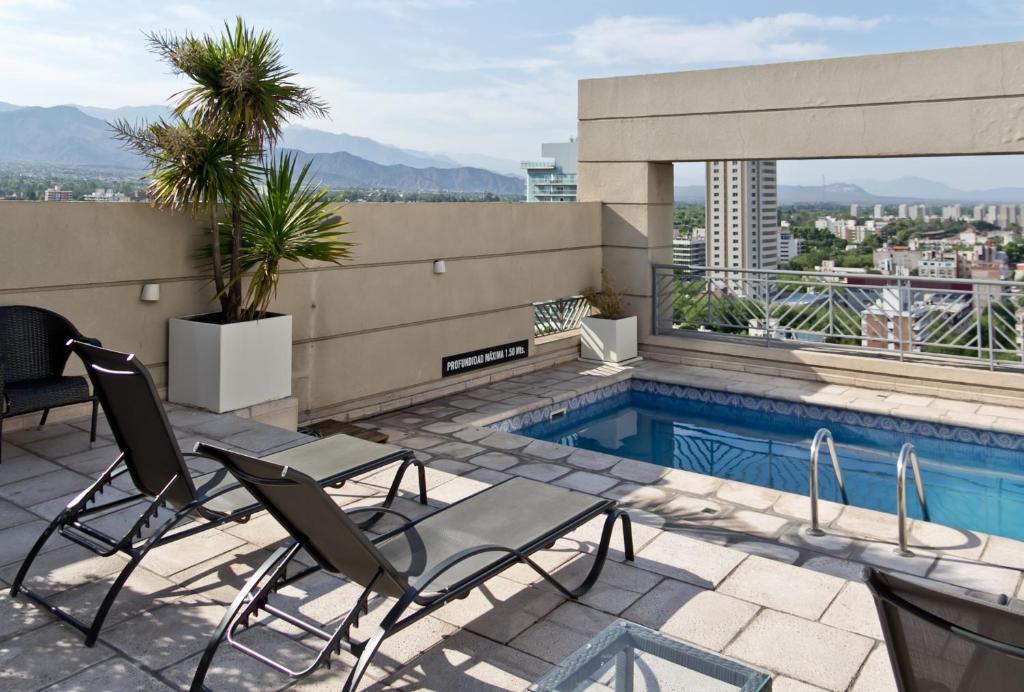 um pátio com cadeiras e uma piscina num edifício em Amérian Executive Hotel Mendoza em Mendoza