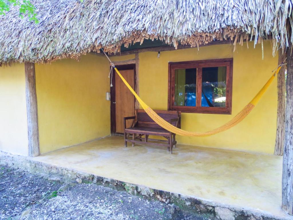 Conhuas的住宿－Cabañas Calakmul，黄色房子前面设有吊床