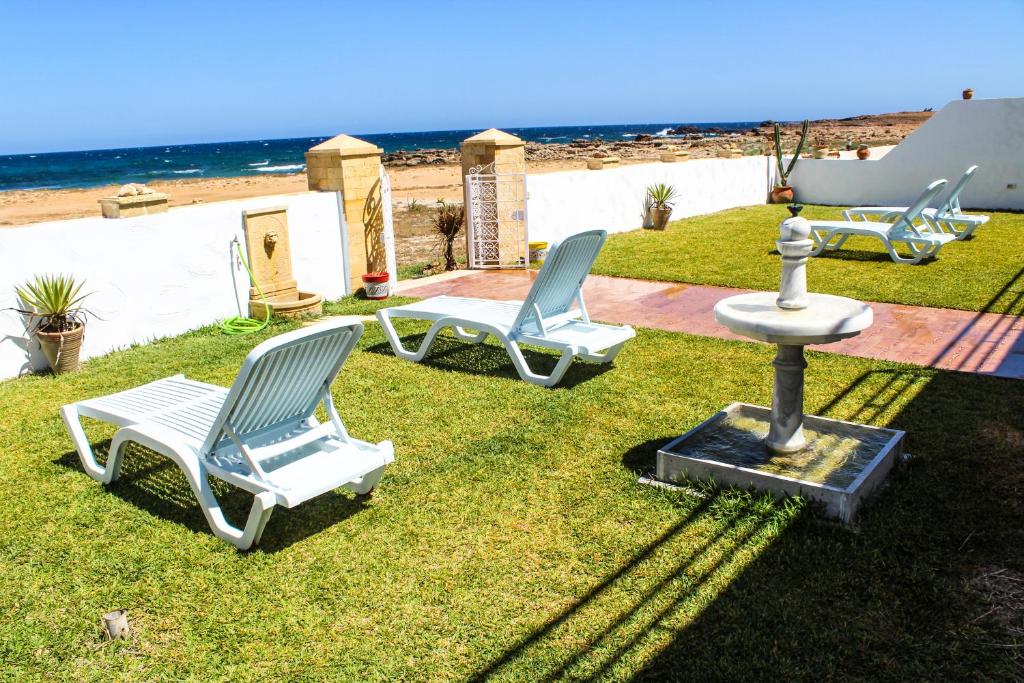 dos sillas y una fuente en la hierba cerca de la playa en Villa Island Zembra, en El Haouaria