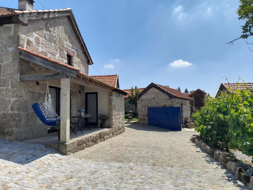 una casa de piedra con una hamaca azul al aire libre en Casas do Arrabalde en Amarante