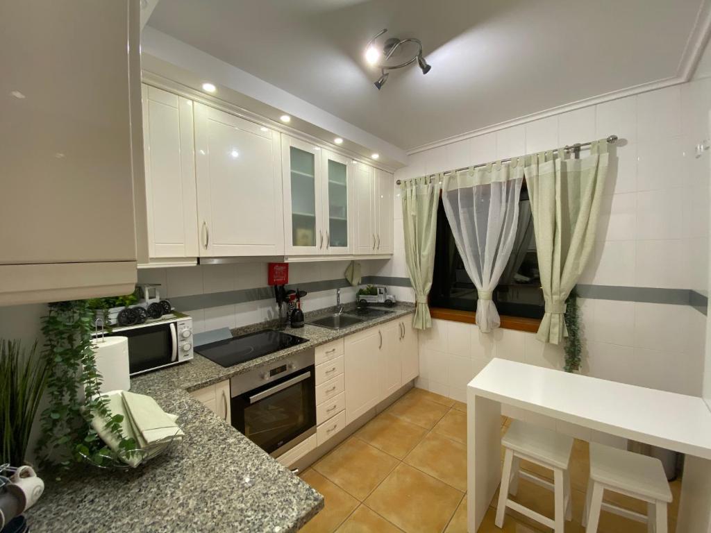 uma cozinha com armários brancos e uma bancada em Vagueira casa férias em Aveiro