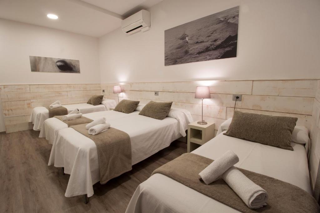 4 camas en una habitación con paredes blancas en Pensión San Martin, en San Sebastián